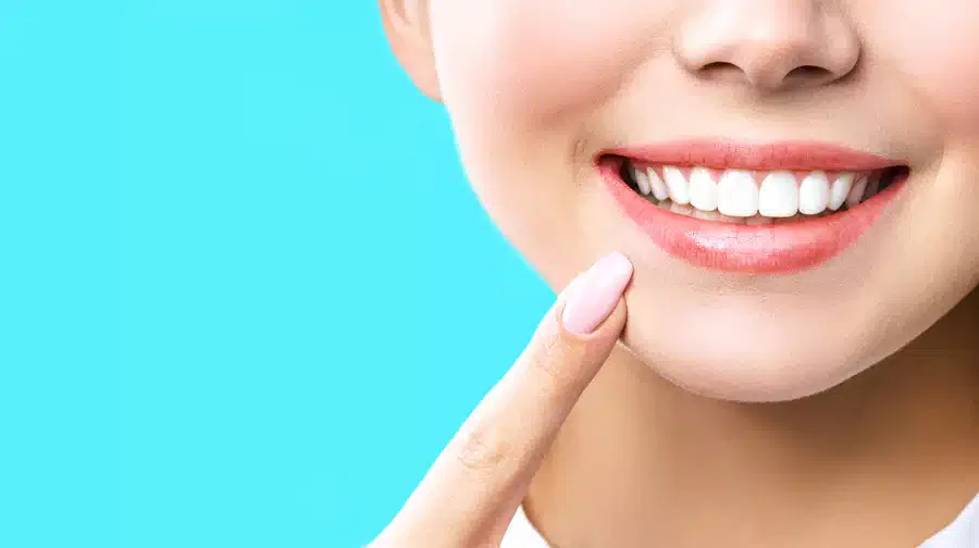 A woman holding her finger to her teeth, looking thoughtful.