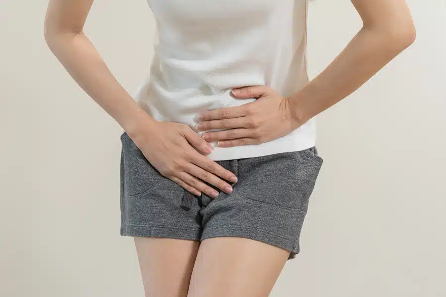 Woman in white t-shirt and denim shorts against a gray background.