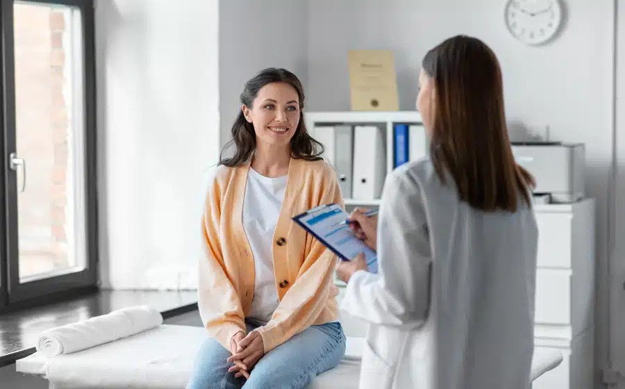 A woman in an orange room conversing with a doctor.
