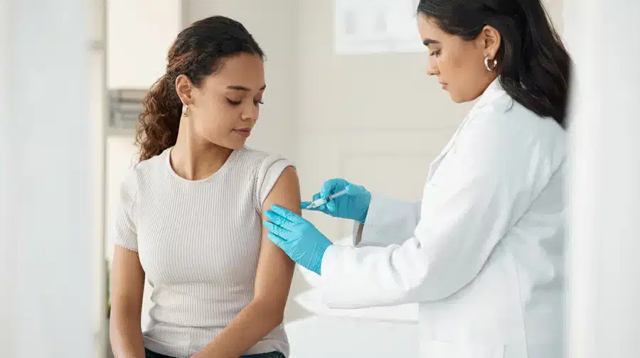 A white woman receiving a medical injection from a doctor.
