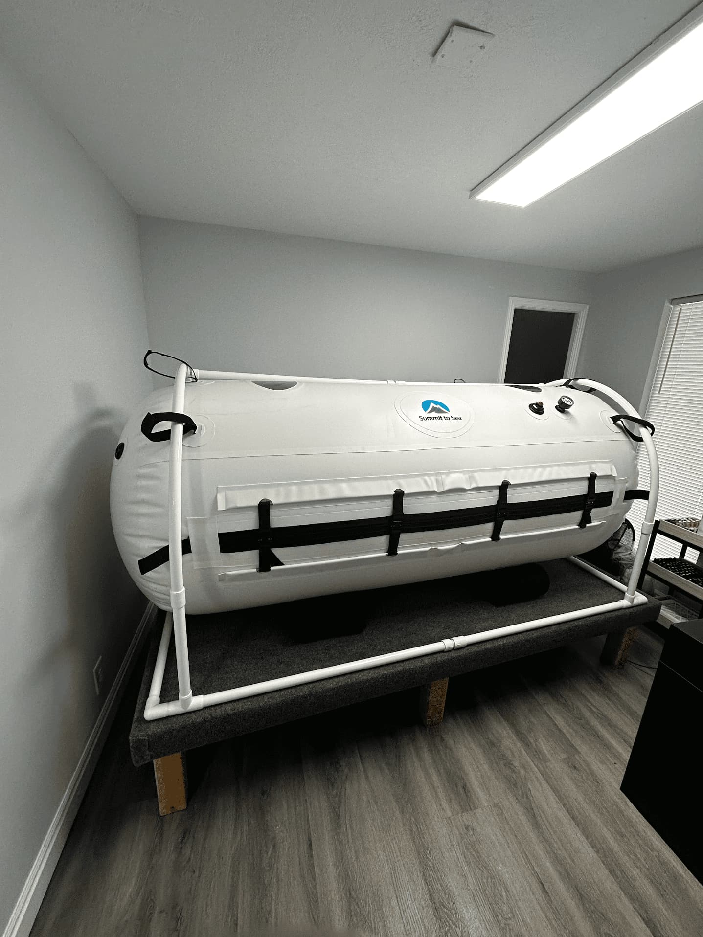 White hyperbaric chamber inside a room with a window. The chamber is labeled "Summit to Sea."