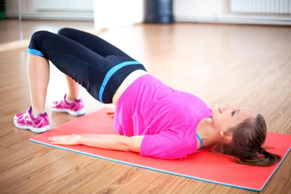 A woman performs a plank exercise on a yoga mat maintaining a straight body alignment and focused expression