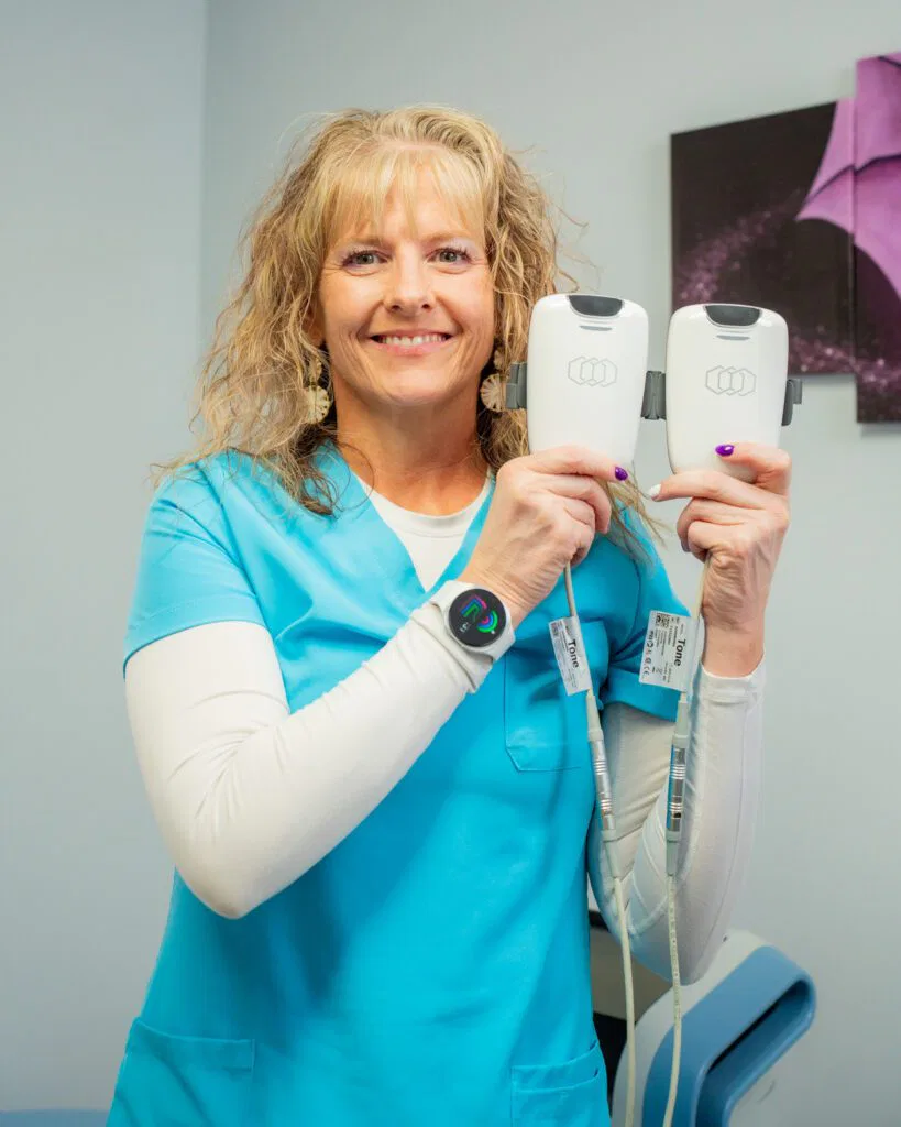 A woman in a blue shirt holds two electronic devices, representing Ivee Restorative Care's technology solutions.