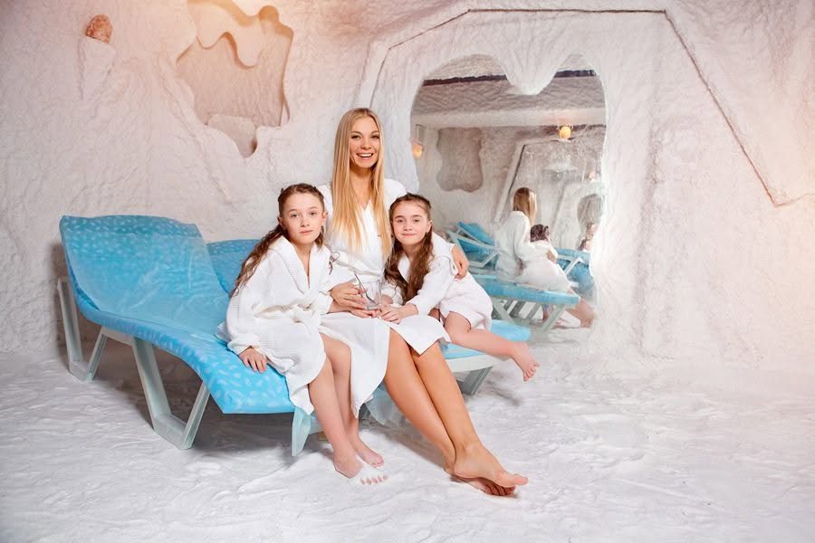 Woman and two children experiencing halotherapy in a snowy room.