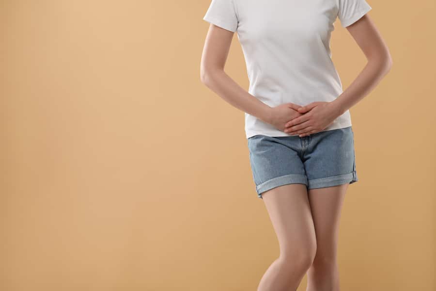 Woman in white t-shirt and denim shorts against a gray background.