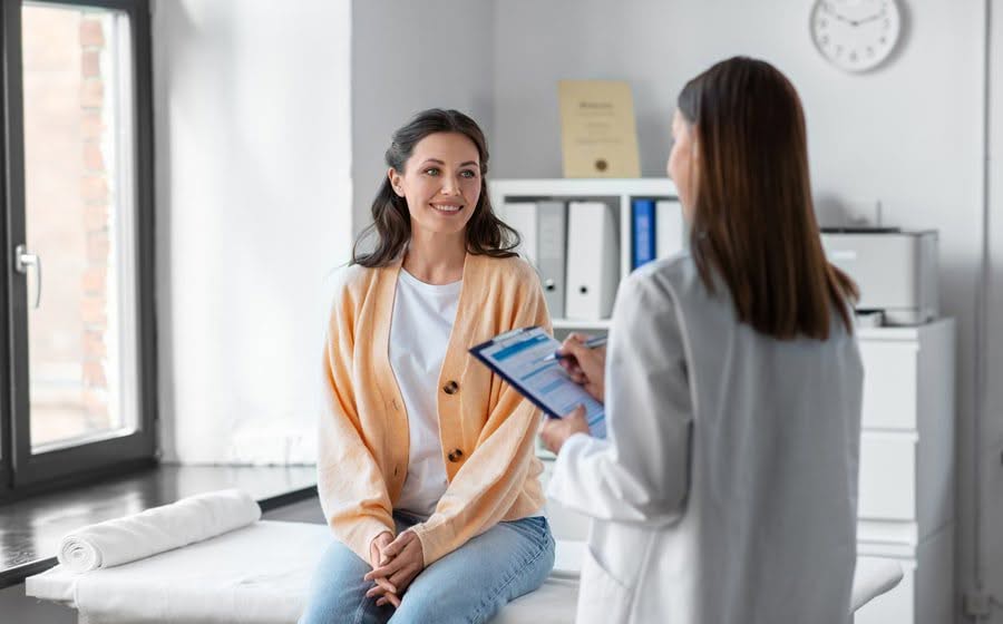 A woman in an orange room conversing with a doctor.