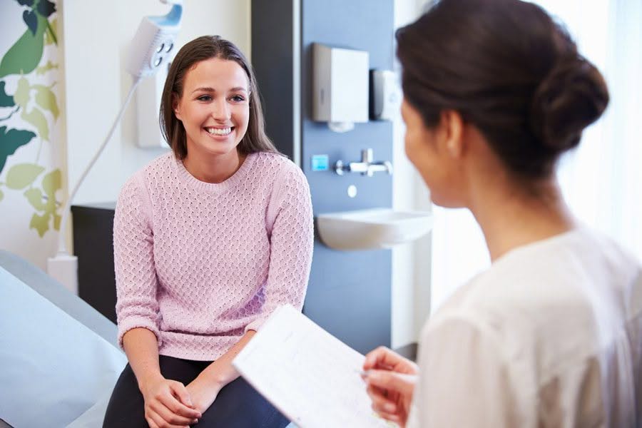 A female patient converses with a doctor in a room, seeking medical advice and discussing her health condition.